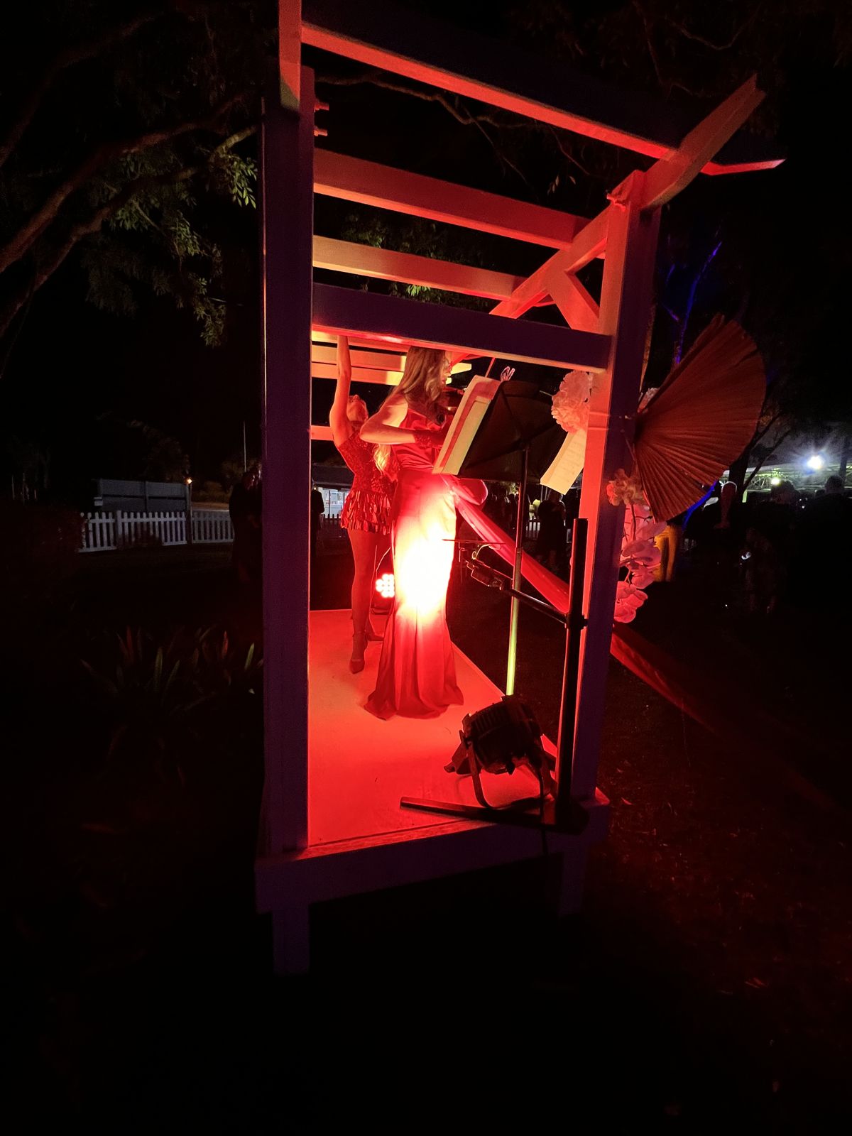 Performer under a red-lit pergola at Corbould Park