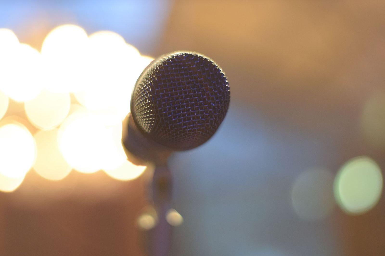 Illustrative image: Microphone on a stand with warm lights behind