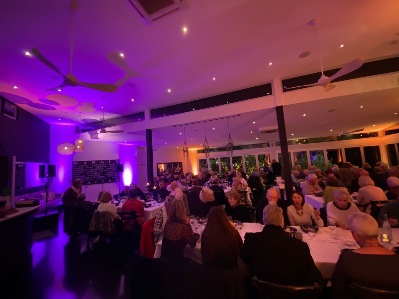 Full house at a dinner show at Noosa Waterfront Restaurant, uplit in purple and amber