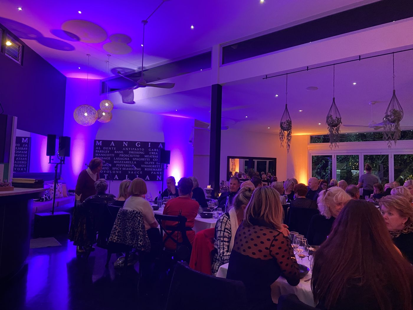 Full house at a dinner show at Noosa Waterfront Restaurant, room uplit in purple