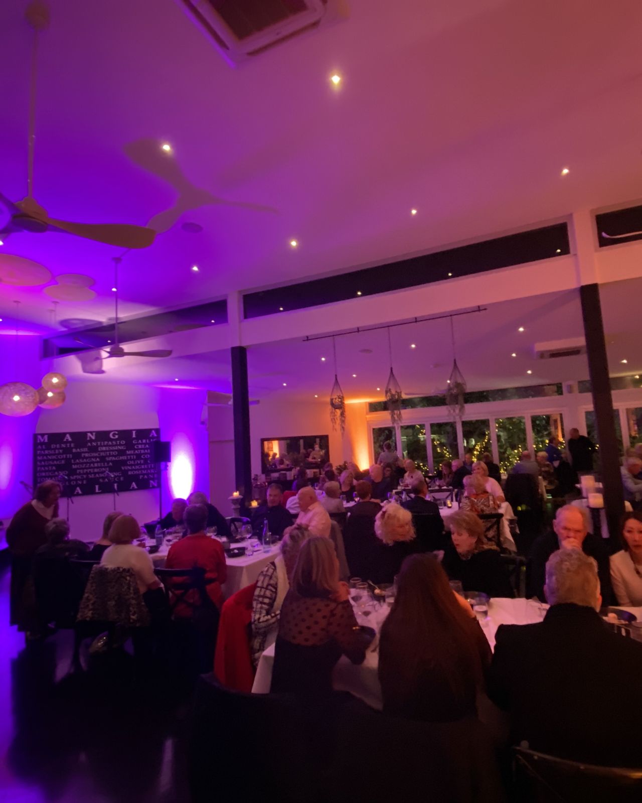 Full house at a dinner show at Noosa Waterfront Restaurant, uplit in purple and amber